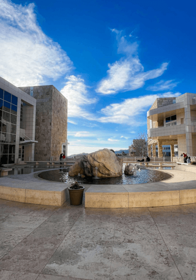 The Getty Center courtyard is a serene open space surrounded by the museum’s sleek white buildings, with tranquil fountains and lush greenery adding to the atmosphere.